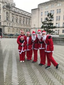 Santas dressed up stood in front of the waterfront in Liverpool.